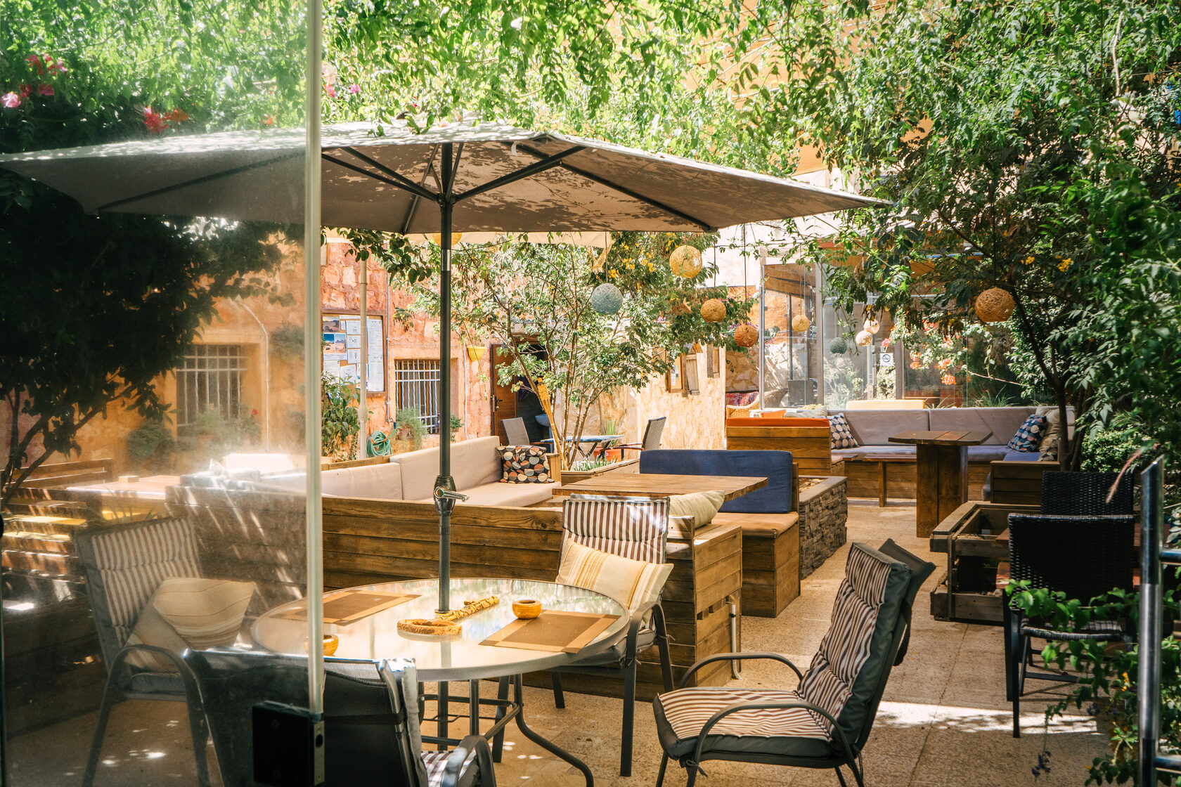 Outdoor terrace workspace with umbrella, wooden tables, and greenery
