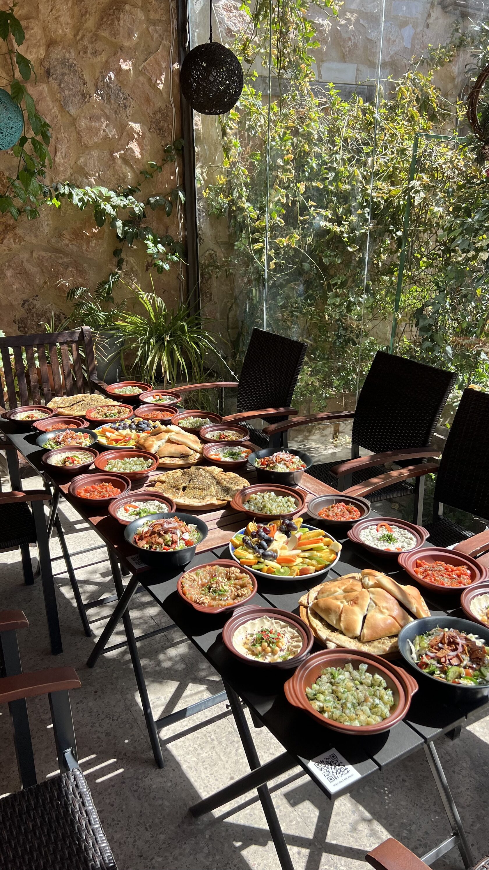 Long table covered with dozens of traditional plant-based dishes in clay bowls on the terrace